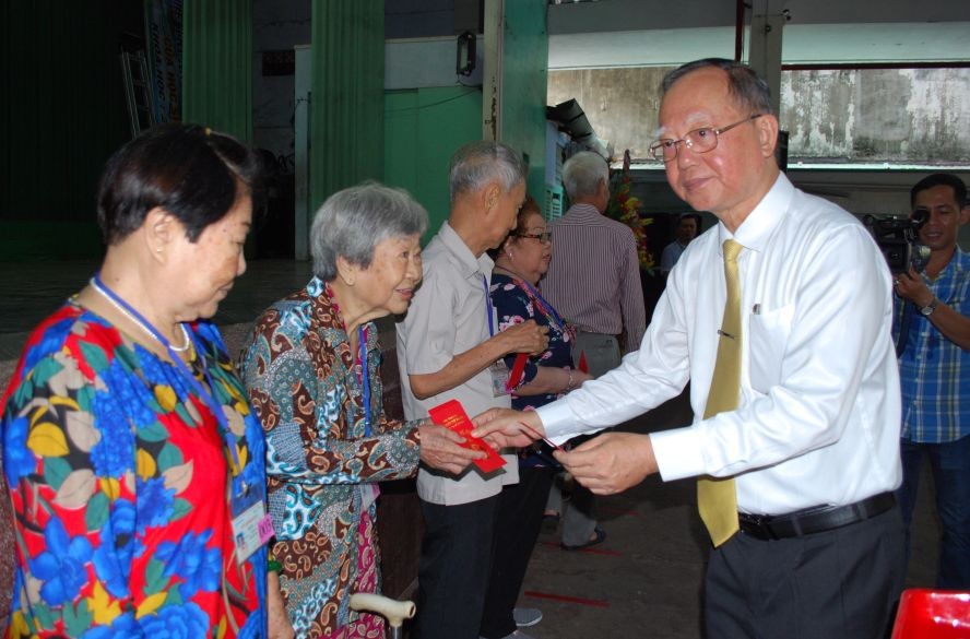 穗城會館理事長盧耀南向高齡鄉親贈送利是。