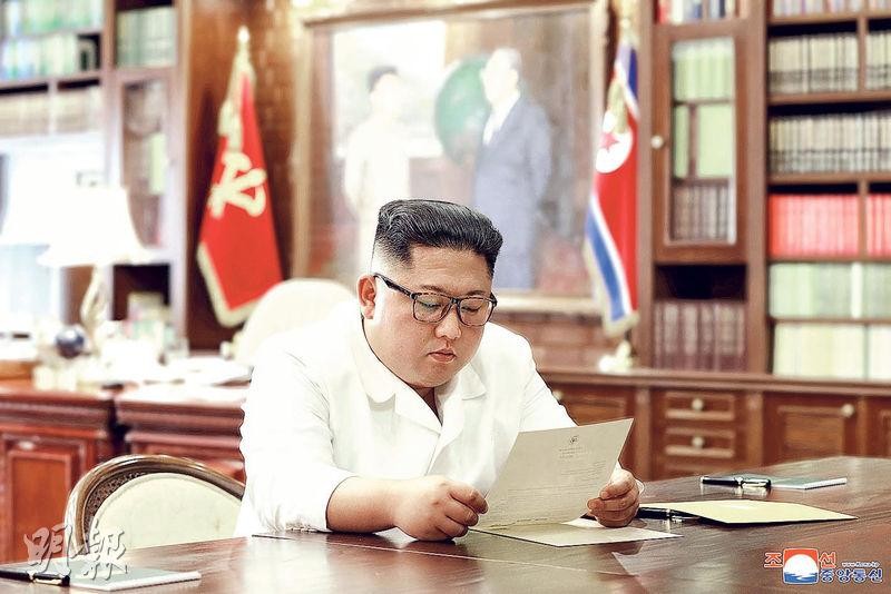 金正恩坐在桌前閱讀特朗普的親筆信。（圖源：KCNA）