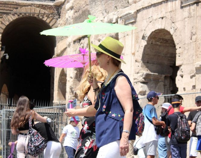 6月28日，在意大利羅馬鬥獸場，人們撐傘遊覽躲避烈日。（圖源：新華社）