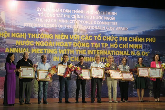 市各友好組織聯合會副主席阮氏紅艷（左一）向有重大貢獻的組織頒發市人委會獎狀。（圖源：明榮）