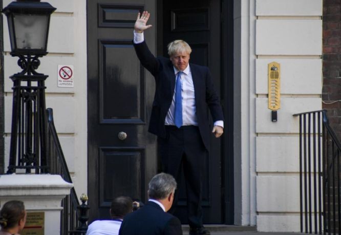 當選英國保守黨領袖的鮑里斯‧約翰遜抵達保守黨總部後揮手。（圖源：新華社）