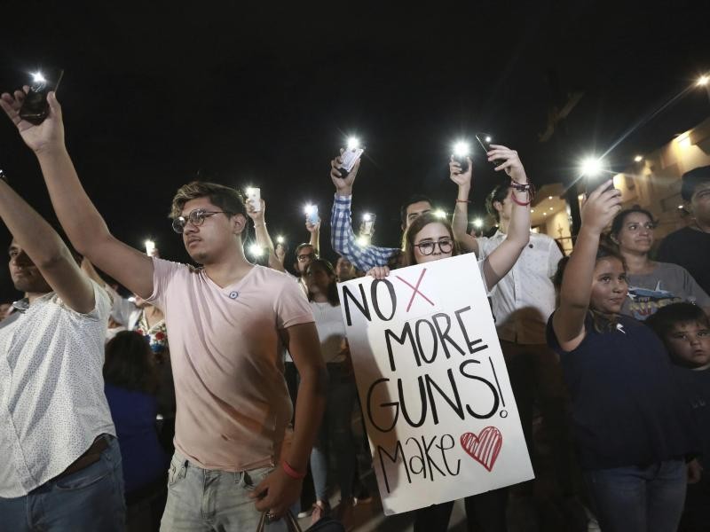 民眾在美墨邊境用手機照明守夜呼籲控槍。（圖源：AP）