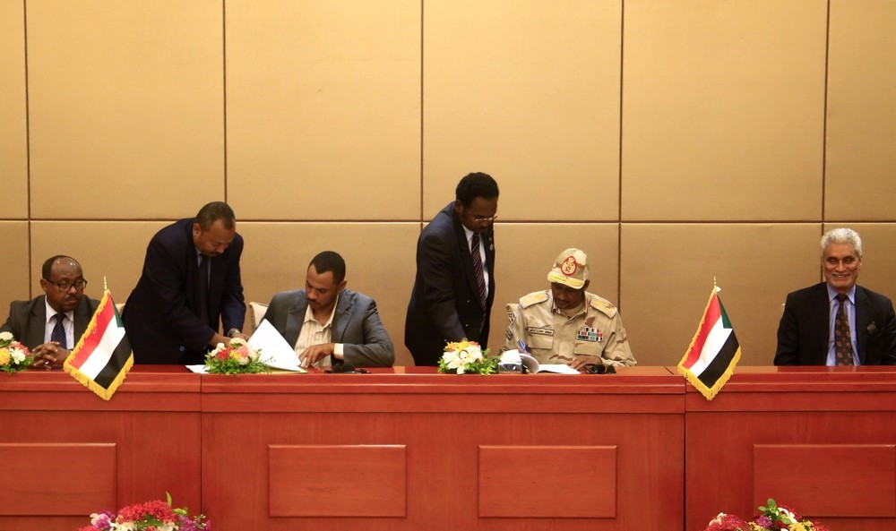 月4日，在蘇丹喀土穆，蘇丹過渡軍事委員會副主席穆罕默德·哈姆丹·達克盧（右二）和“自由與變革聯盟”主要領導成員艾哈邁德·拉比（左三）簽署協議。（圖源：新華社）