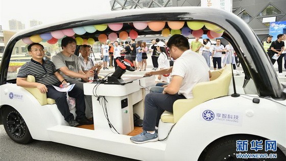 8月28日，在“5G自動駕駛科技示範體驗”活動現場，重慶市民在一輛自動駕駛汽車挑戰賽的參賽車輛上進行5G自動駕駛真實城市道路試乘體驗。（圖源：新華社）