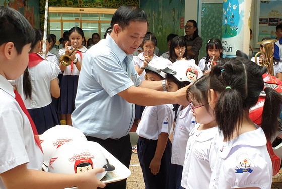 明道小學校長阮忠海給一年級小學生戴安全帽。
