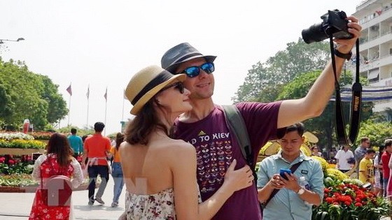 一對外籍情侶遊客在阮慧步行街上自拍紀念照。（圖源：越通社）
