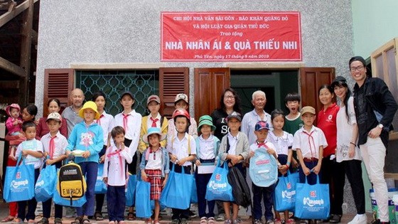西貢作家分會成員們與清貧好學生、阮玉英在仁愛屋前合影。