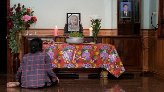 圖為英國卡車藏屍案的一名遇難者裴氏絨家屬在其遺像前表示沉痛哀悼。（圖源：AFP）