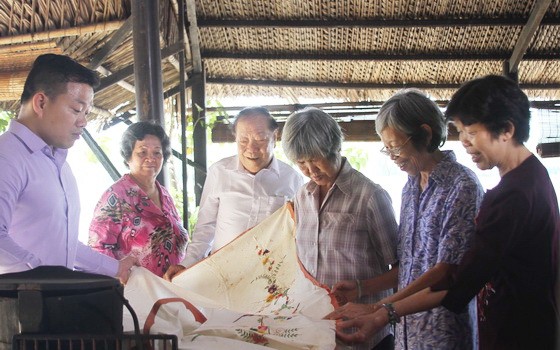 文物捐贈者在觀看劉麗英老師（右二）捐贈其母親昔日的嫁妝床簾。