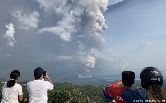 當地時間1月12日，菲律賓馬尼拉西南卡維特省的塔蓋泰鎮，民眾在給爆發的火山拍照。（圖源：AFP）