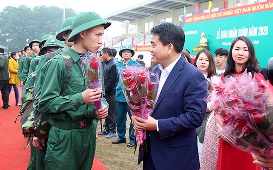 河內市人委會主席阮德鐘（前右）向新兵贈花慰勞。（圖源：雲英）