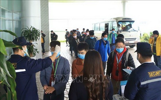 永福省伯山工業區越南Compal有限公司的所有員工需佩戴口罩並排隊依次測量體溫後才進門上班。（圖源：越通社）