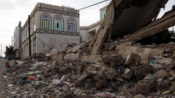 2月14日，在也門首都薩那，當地居民走過一處房屋廢墟。（圖源：新華社）