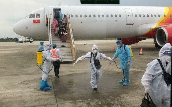 從印尼撤回的越南公民，乘客下機時接受噴灑消毒後送至集中隔離區進行醫學隔離觀察。（圖源：QCD）