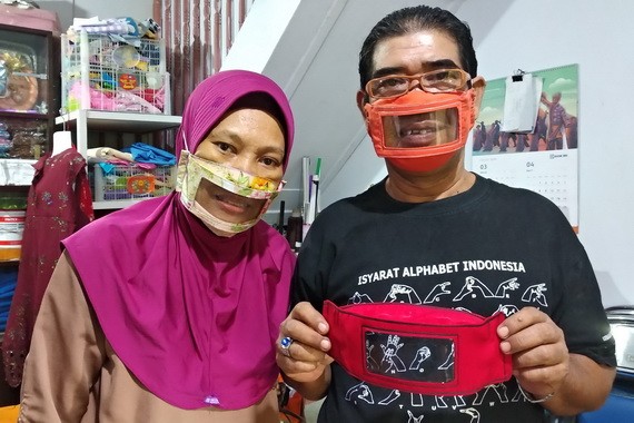圖為夫妻倆展示製作的透明口罩。（圖源：AFP）