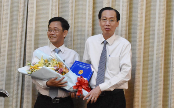 陳光草同志（左）從市人委會常務副主席黎清廉手中接過人事委任《決定》和祝賀鮮花。（圖源：進龍）