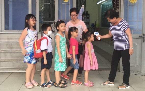 崇華華文中心老師向每班學生測量體溫。