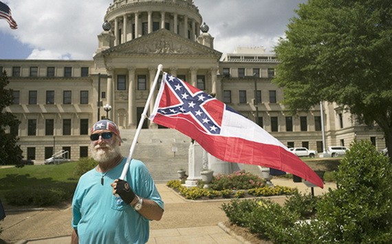 圖為 6月28日，一名反對更換州旗的男子手持舊州旗站在州議會大廈前。（圖源：新華社）