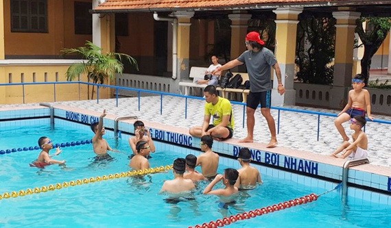 運動員梁玉維正在教孤兒學游泳。