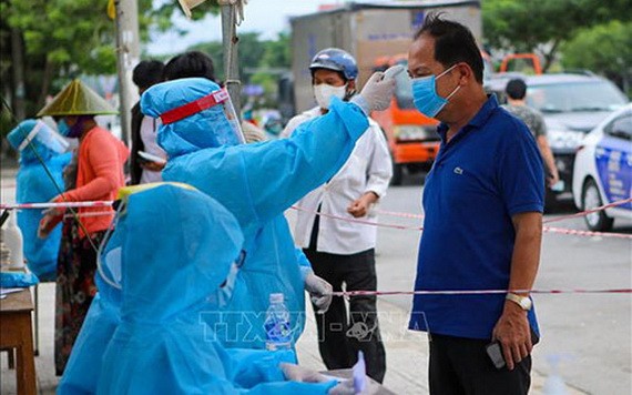 防疫工作人員給峴港市五行郡市民測量體溫。（圖源：越通社）