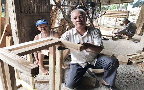 裴文盧（中）與慈善木匠組成員們在釘造凳子。