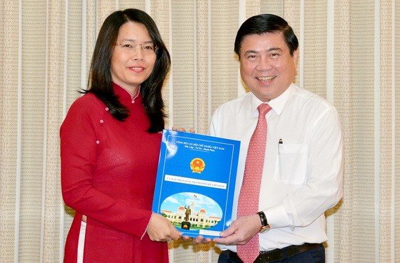 新任市旅遊廳長阮氏映華（左）從市人委會主席阮成鋒手中接過人事委任《決定》。