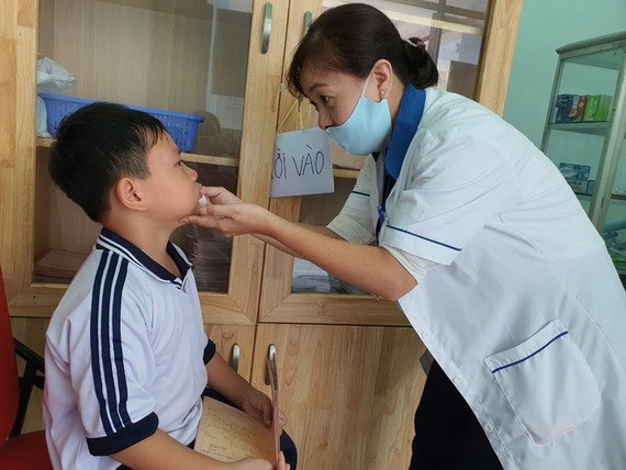 星花小學校醫務老師武碧娥在給一名小學生處理下巴的擦傷。