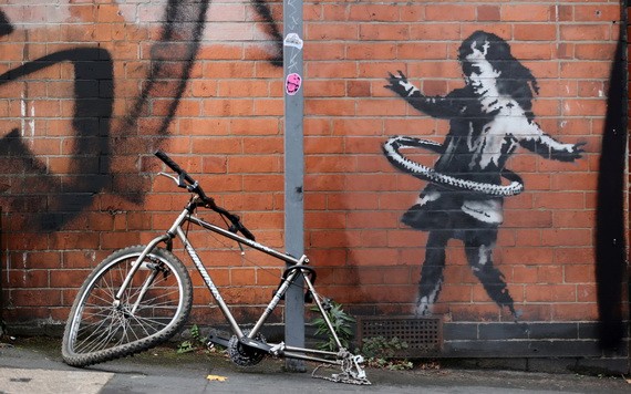 英國知名塗鴉藝術家班克西（Banksy）最新作品，描繪一名小女孩把腳踏車輪胎當呼拉圈搖。（圖源：路透社）