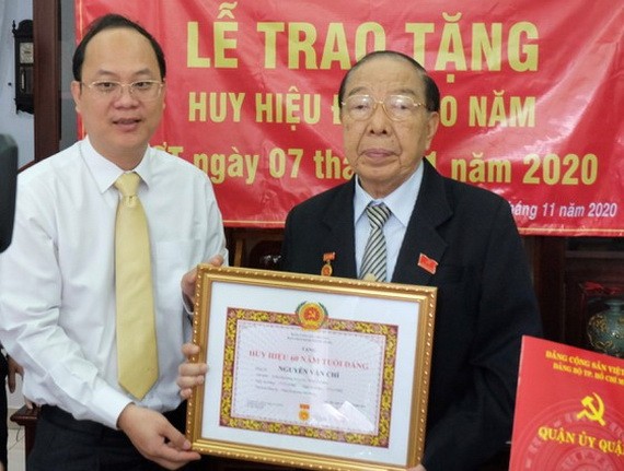 市委副書記、市委組織處主任阮胡海向阮文志同志（右）頒授60年黨齡紀念章。（圖源：梅花）