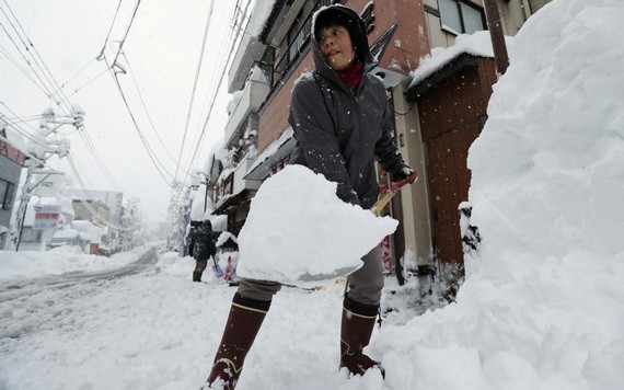 一名女子在日本新潟縣湯澤的街頭鏟雪。（圖源：路透社）