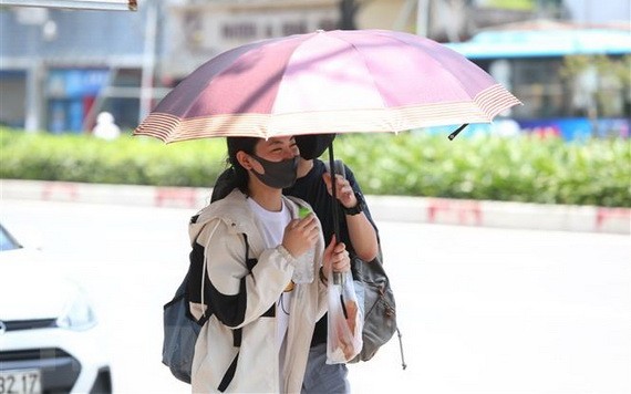 一對情侶撑著伞走在烈光下。（圖源：越通社）