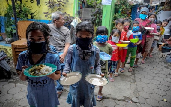 圖為去年4月10日，印尼西爪哇省萬隆市的居民戴著口罩，拿著盤子排隊領取免費食物。 （圖源：路透社）