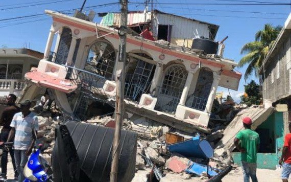 8月15日，在海地萊凱，人們站在一棟被地震損毀的房屋前。（圖源：新華社）