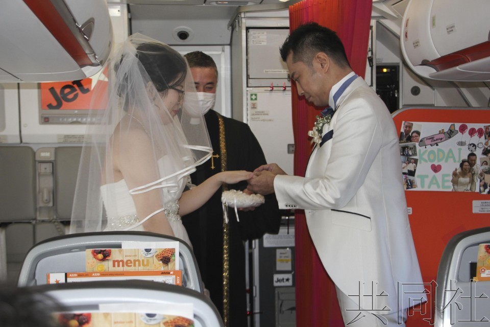 新郎和新娘在飛行中的包機航班機艙內舉行“空中婚禮”，交換戒指。