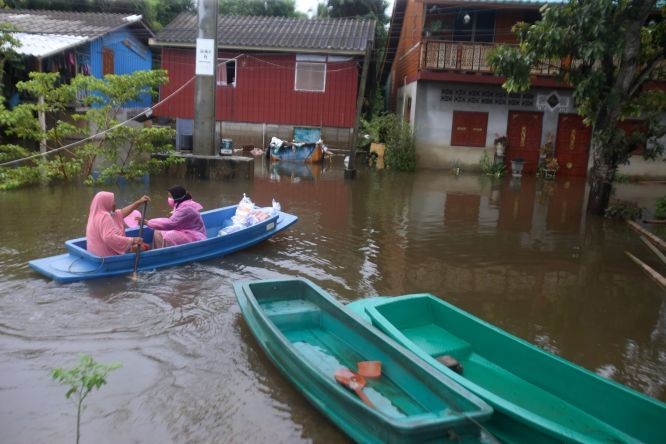 泰國北大年府發生水災，村民乘船渡過洪水。（圖：馬新社）