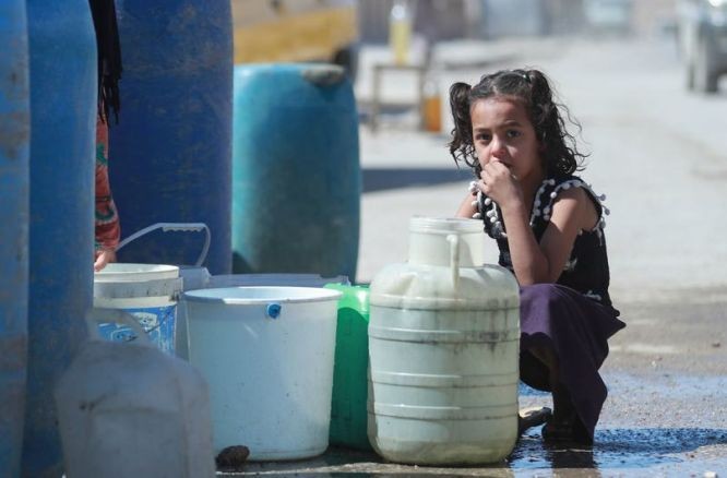 在敘利亞東北部哈塞克市，一名女童蹲在運水站旁邊。（圖：聯合國）