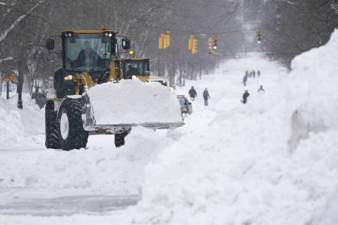 圖為26日，工人們使用重型設備清理紐約州水牛城里士滿大道的積雪。