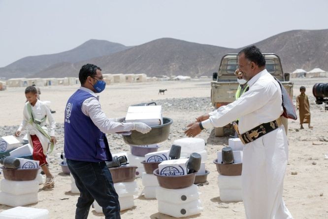 在也門的馬里布，移民組織的一名工作人員向新的流離失所社區分發援助包。（圖：聯合國）