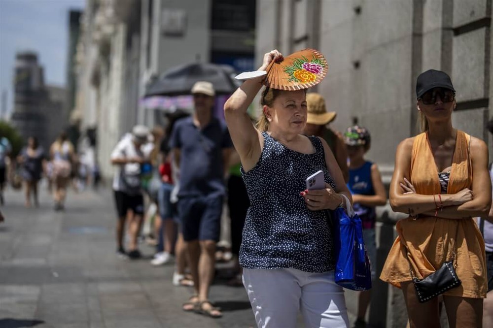图为去年7月18日马德里街头民众在高温下试图遮蔽豔阳。（图：AP）