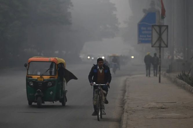 周一清早在印度首都新德里，通勤者在雾霾笼罩的街道前行。（图：AFP）