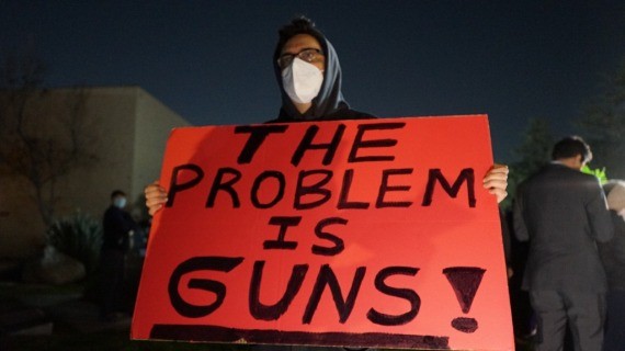 一名男子手持抗议枪枝暴力的标语牌。（图：新华社）