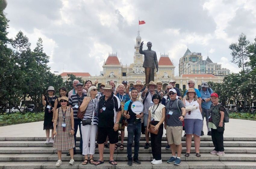 前来本市的国际游客越来越多。图为游客在市人委会办公厅前的胡伯伯纪念碑拍照留念。