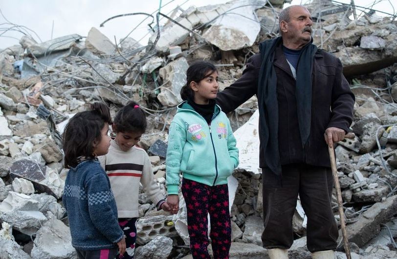 在叙利亚西北部，一个家庭站在他们被摧毁的房子废墟前。（图：联合国）
