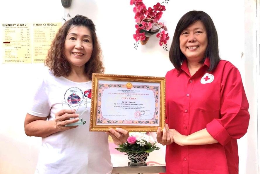 第六郡红十字会主席黎氏宝庄向何丽娟（左）颁奖。