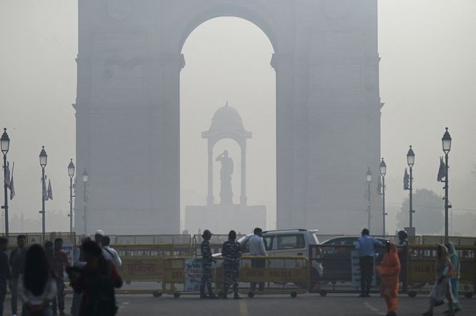 当地时间2022年11月3日，印度新德里，雾霾弥漫，大气污染严重，行人在印度门附近的一条道路上行走。（图：互联网）