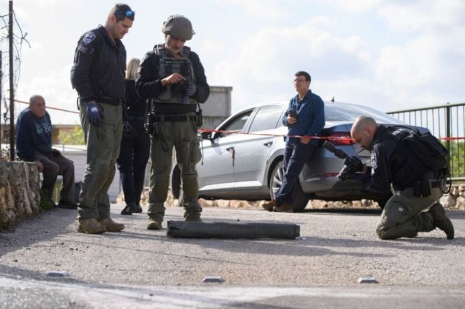 在以色列北部安全人员检查一枚火箭弹残骸。（图：新华社）