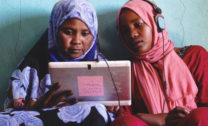 苏丹两名年轻女子在太阳能平板电脑上玩教育游戏。（图：儿基会）