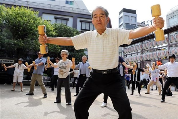 日本东京老人手举木质哑铃锻炼身体。（图：AFP）