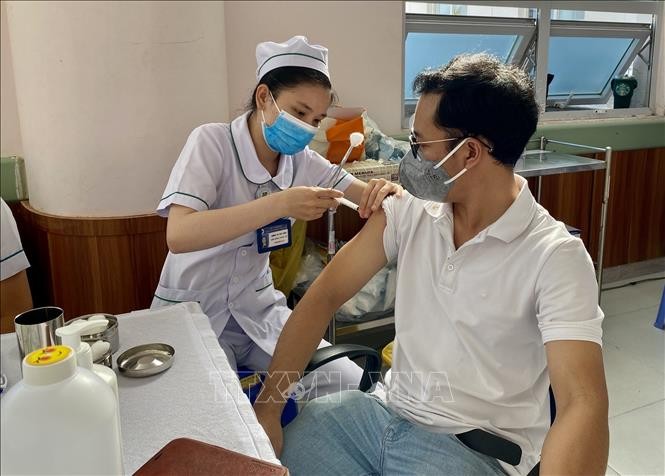 一名男性在接受新冠疫苗加强针。（图：越通社）