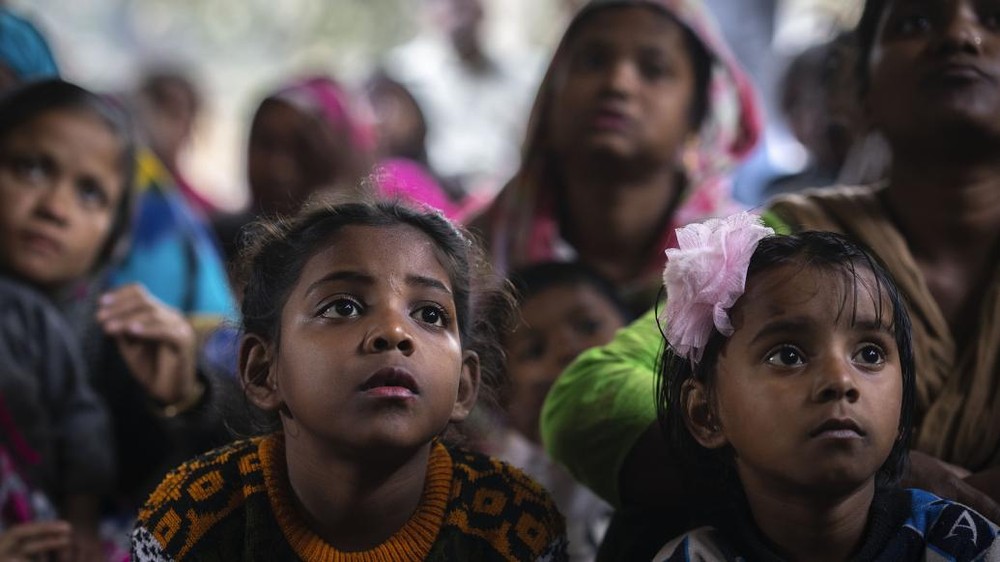 在印度古瓦哈提 (Guwahati) 的一个棚户区，女孩和她们的母亲正在一个关于童婚问题的宣传营中听取一名非政府组织工作人员的讲话。（图：AP）